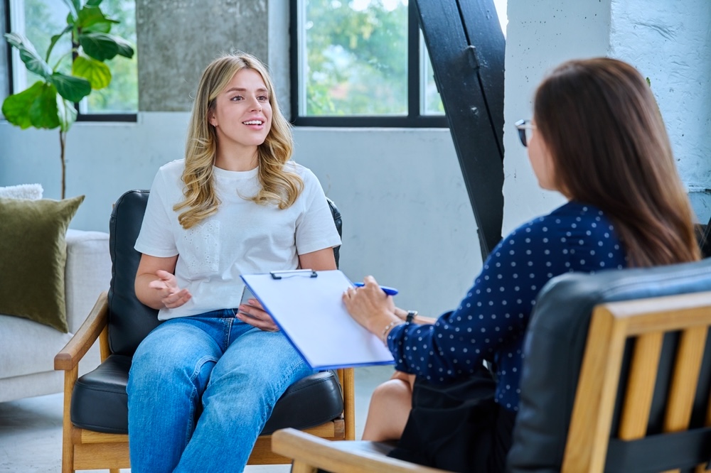 Adult woman speaking with psychologist in a dual diagnosis program for addiction and mental health