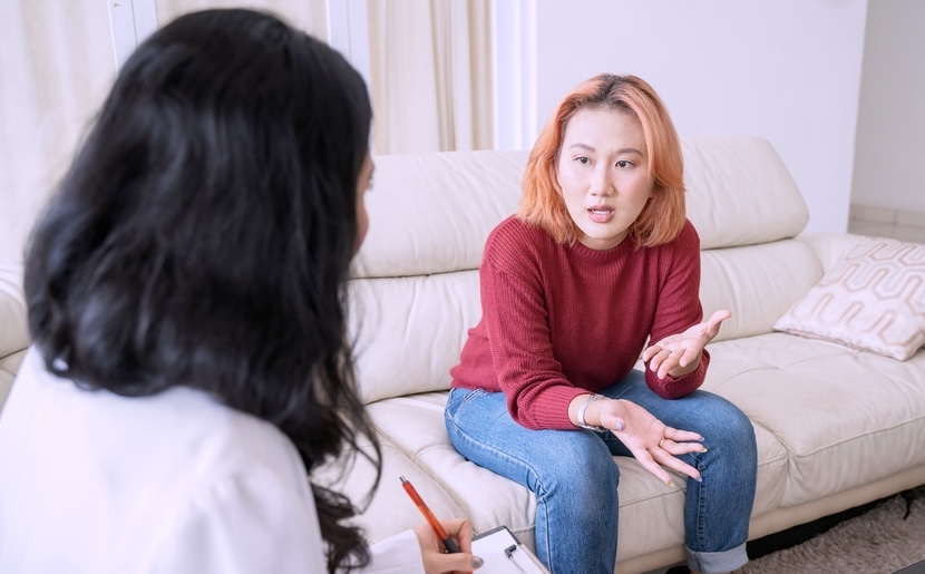 Young female with red shirt speaking to a therapist in a boutique rehab